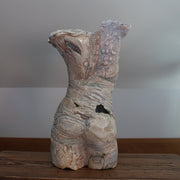 the rear view of a textured ceramic torso made by Pauline Lee standing on a wooden table 