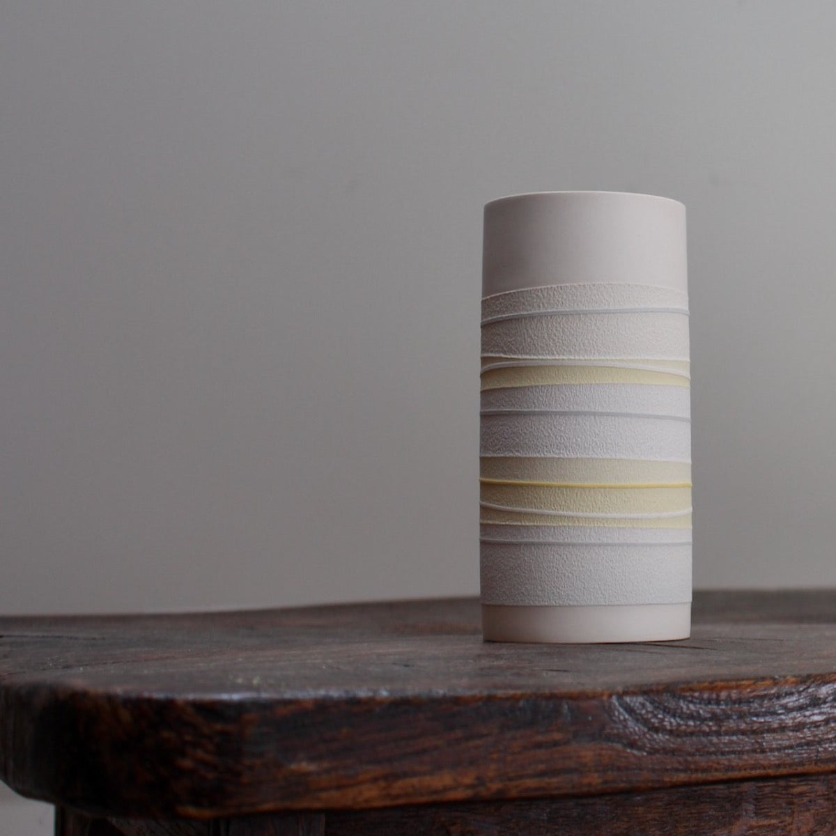 white ceramic vase with pale yellow stripes 