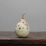 A large ceramic white pear with orange floral detail and a gold stalk by ceramic artist Remon Jephcott
