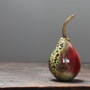 A ceramic red and green pear with glaze details and a gold stalk by ceramic artist Remon Jephcott.