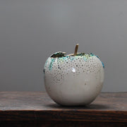 A large ceramic white apple with a gold stalk by ceramic artist Remon Jephcott