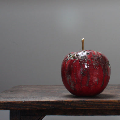 A large ceramic red apple with a gold stalk by Remon Jephcott.