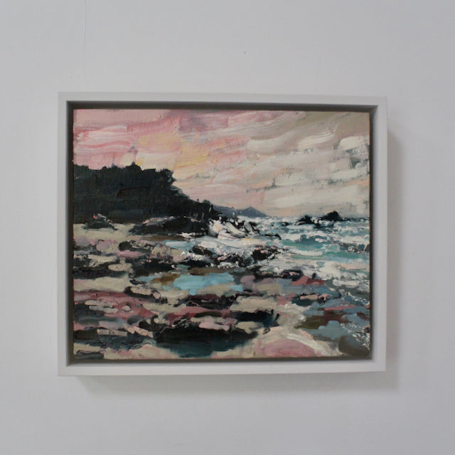 a framed painting of a stormy sea in blues and whites, pink and grey rocks and a view of the Rame Head headland it is by artist Jill Hudson.