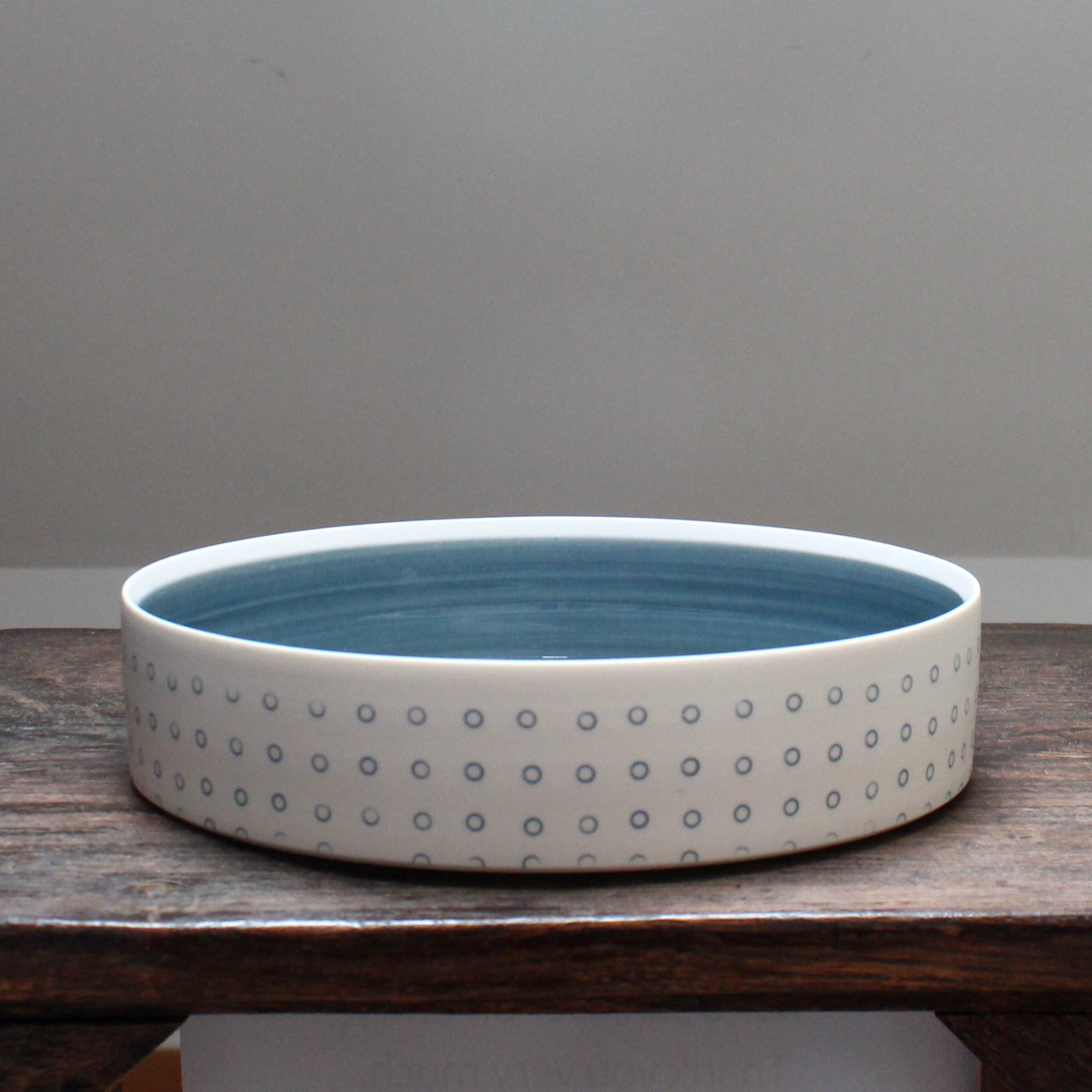 a porcelain serving dish decorated with with blue dots and a blue interior.