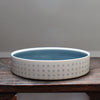a porcelain serving dish decorated with with blue dots and a blue interior.