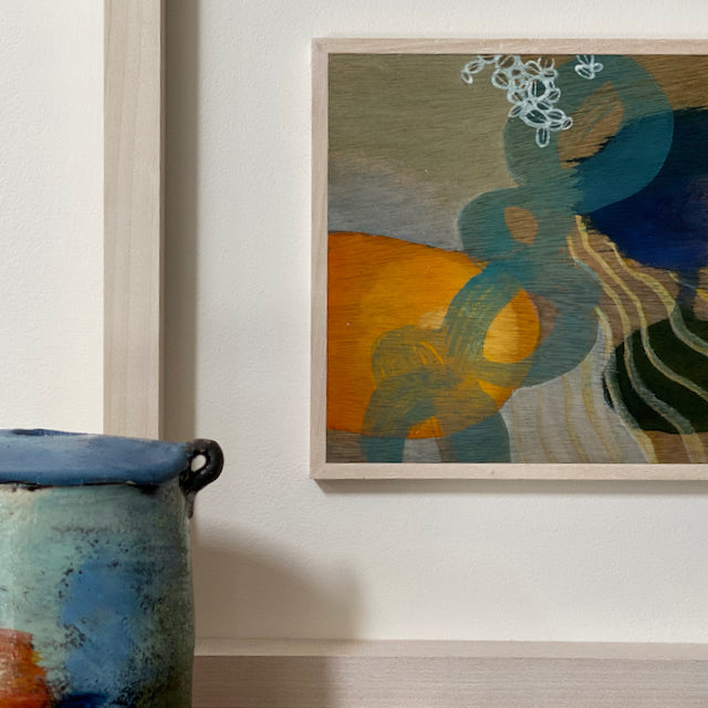 framed abstract painting by Tara Leaver inspired by shapes and colours under the sea, oranges blues and purples  next to ceramic pot in blues and oranges by John Pollex