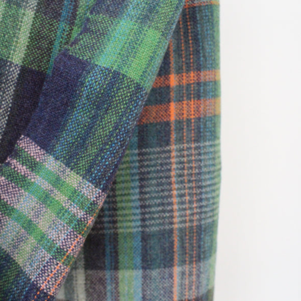 close up detail of a woollen hand-woven scarf in greens, blue and an orange stripe by textile artist Teresa Dunne
