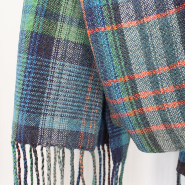 small part of a woollen hand-woven scarf in greens, blue and an orange stripe by textile artist Teresa Dunne.