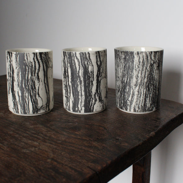  trio of small ceramic beakers by UK ceramicist Heidi Harrington with a black and white photo image of tree bark on the the exterior and cream glazed interior 