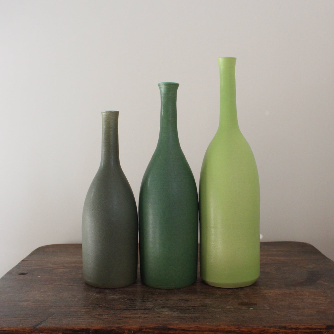 three ceramic bottles in different shades of green and incremental sizes by Lucy Burley ceramicist