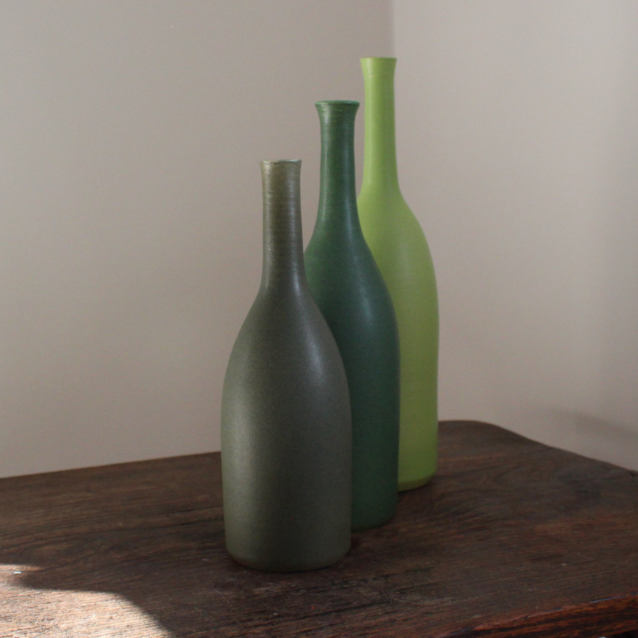 a trio of ceramic bottles in different shades of green and incremental sizes by Lucy Burley UK ceramicist