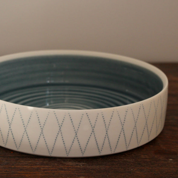 white porcelain serving dish with blue interior and blue diamond pattern on outside it's by Kathryn Sherriff of By the Line Pottery , England.