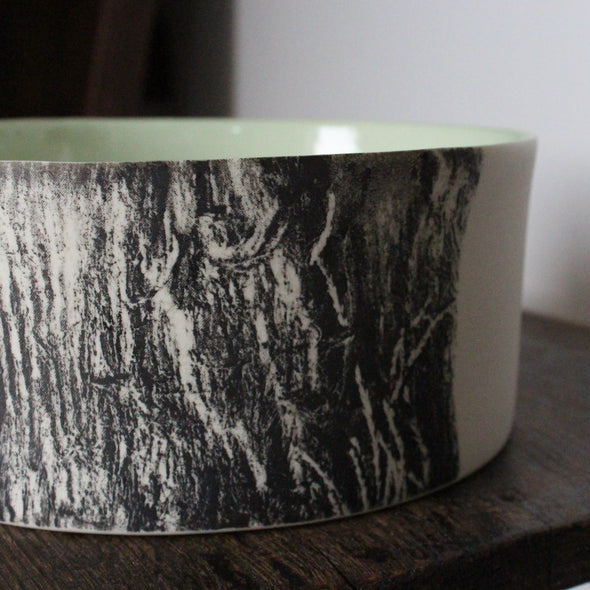 close up detail of a round ceramic bowl with a green interior glaze and a black and white tree bark effect on exterior by UK ceramicist Heidi Harrington 