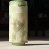 a tall cylindrical ceramic vessel in green glaze decorated with yellow flowers made by ceramicist Emily-Kriste Wilcox.