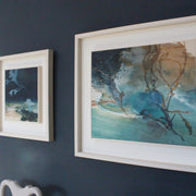 two abstract paintings in shades of blue in white frames on a dark blue wall they are by Cornwall artist Tara Leaver 