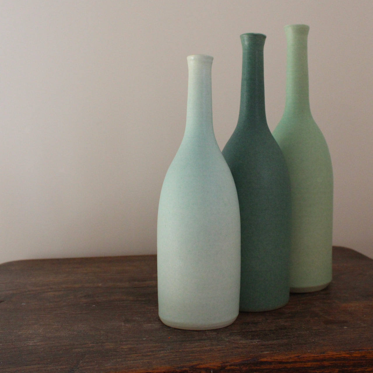three ceramic bottles in different shades of turquoise and incremental sizes by Lucy Burley ceramicist