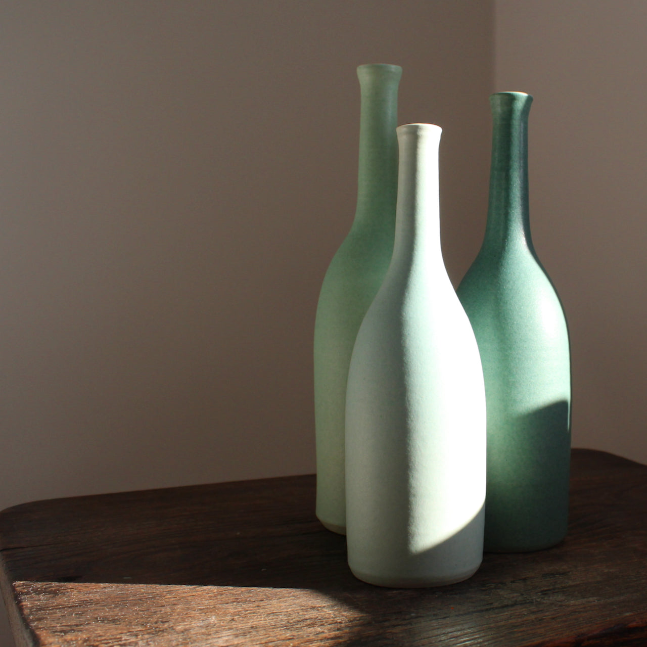 a set of three ceramic bottles in different shades of turquoise and incremental sizes by Lucy Burley UK ceramicist.